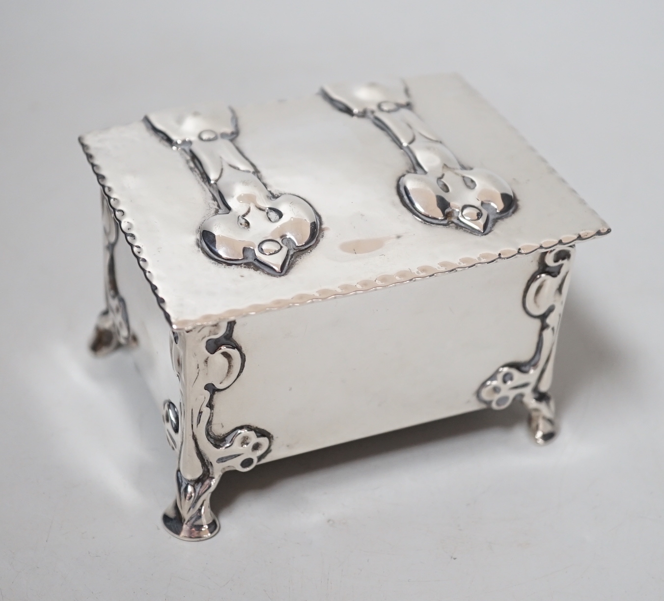 An Edwardian Arts & Crafts Kate Harris for William Hutton & Sons rectangular silver box, of lidded casket form, with relief cast foliate bracket feet, strap hinges and cedar lined interior, London, 1902, width 10.2cm, gr